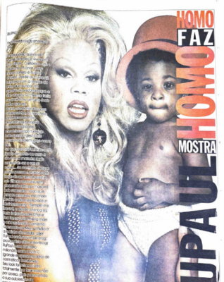 Na décima quarta página da 11ª edição do Babado, publicada em 1997, a coluna Homo Faz, Homo Mostra, traz um texto sobre a drag queen Rupaul. Ao fundo, há uma imagem da artista montada com uma peruca loira, batom vermelho e brincos grandes, segurando um bebê negro de fraldas que usa um chapéu coco vermelho.